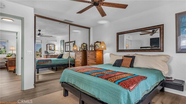 bedroom featuring ceiling fan, a closet, visible vents, and wood finished floors