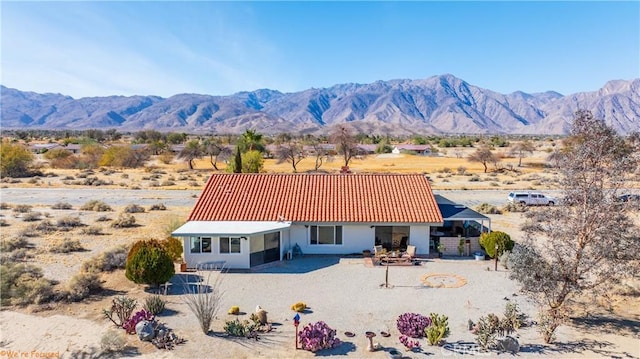 back of property featuring a tiled roof, driveway, a mountain view, and stucco siding