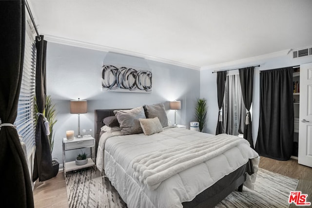 bedroom featuring ornamental molding and light wood-type flooring