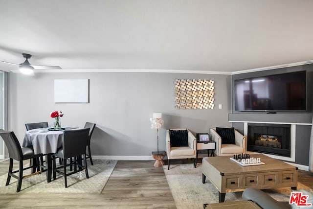 living room with light hardwood / wood-style floors, ceiling fan, and ornamental molding