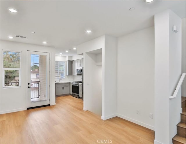 kitchen featuring gray cabinets, sink, light hardwood / wood-style flooring, and appliances with stainless steel finishes