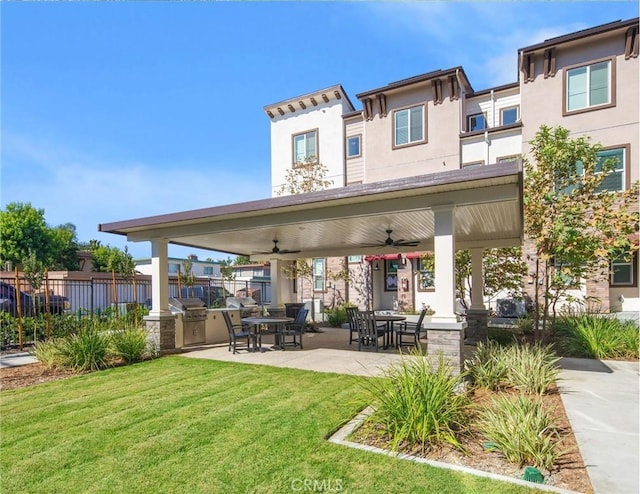 rear view of property featuring ceiling fan, a patio area, exterior kitchen, and a yard