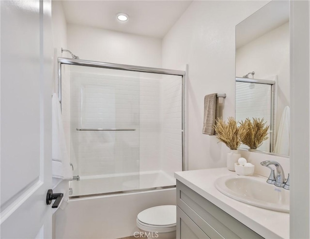 full bathroom featuring vanity, toilet, and bath / shower combo with glass door