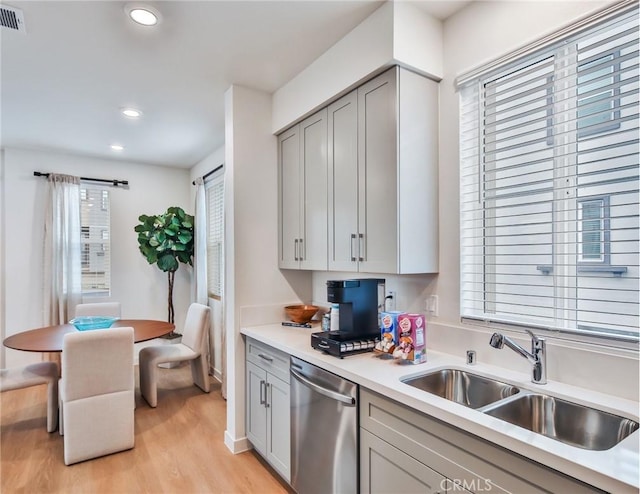 kitchen featuring gray cabinetry, light hardwood / wood-style flooring, stainless steel dishwasher, and sink