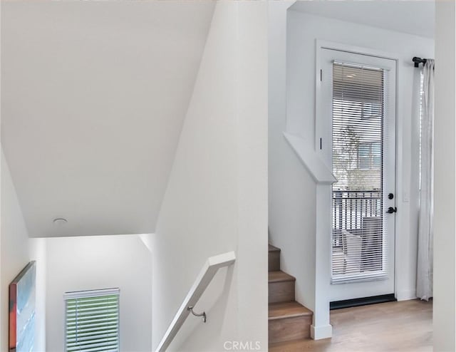 stairway with hardwood / wood-style floors and lofted ceiling