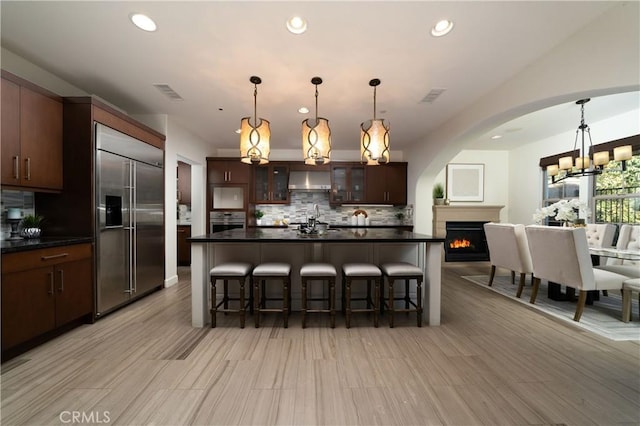 kitchen with decorative backsplash, appliances with stainless steel finishes, dark brown cabinetry, a kitchen island, and a breakfast bar area