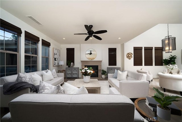 living room featuring ceiling fan, a large fireplace, and hardwood / wood-style flooring