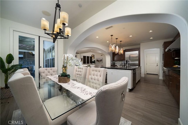 dining area featuring wood-type flooring, a notable chandelier, and sink