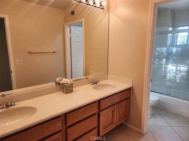 full bathroom with combined bath / shower with glass door, vanity, tile patterned floors, and toilet