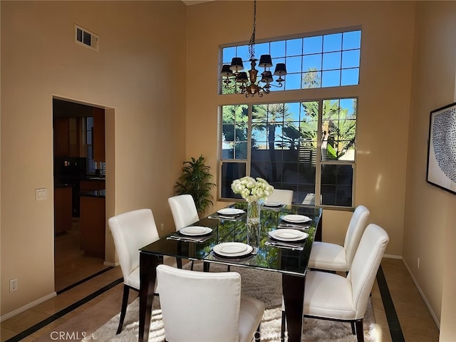 tiled dining area featuring a chandelier and a high ceiling