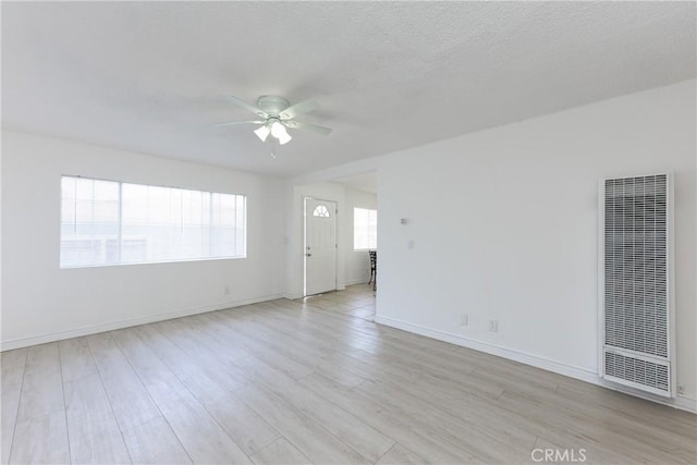 spare room with a textured ceiling, ceiling fan, and light wood-type flooring