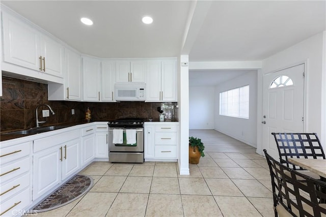 kitchen featuring light tile patterned flooring, tasteful backsplash, white cabinetry, sink, and stainless steel gas range