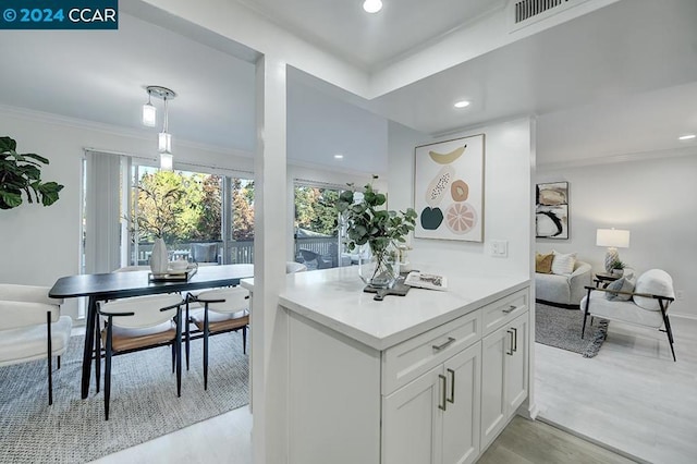 kitchen featuring white cabinets, light hardwood / wood-style floors, and crown molding