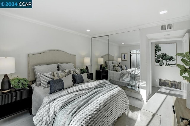 bedroom with light hardwood / wood-style floors, ornamental molding, and a closet