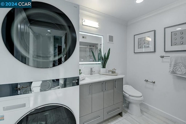 bathroom featuring ornamental molding, vanity, a shower with door, stacked washer and dryer, and toilet