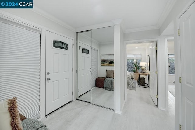 entryway with light wood-type flooring and ornamental molding