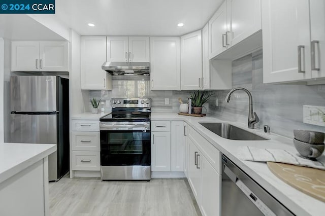 kitchen with white cabinetry, sink, stainless steel appliances, decorative backsplash, and light wood-type flooring