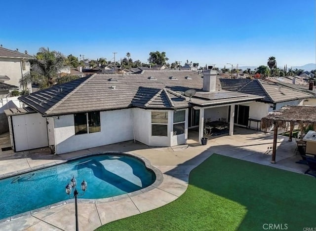 rear view of house with a patio area, a tiled roof, an outdoor pool, and stucco siding