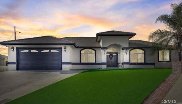 view of front of property with concrete driveway, a lawn, an attached garage, and stucco siding