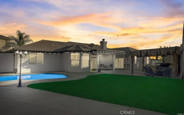 rear view of house with a yard, a patio area, and an outdoor pool