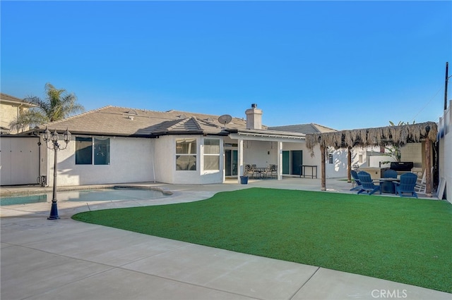 back of property with a chimney, a lawn, a patio area, and stucco siding