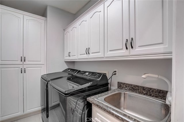 clothes washing area featuring cabinet space, separate washer and dryer, and a sink