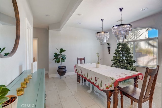 dining space with an inviting chandelier, light tile patterned floors, and baseboards