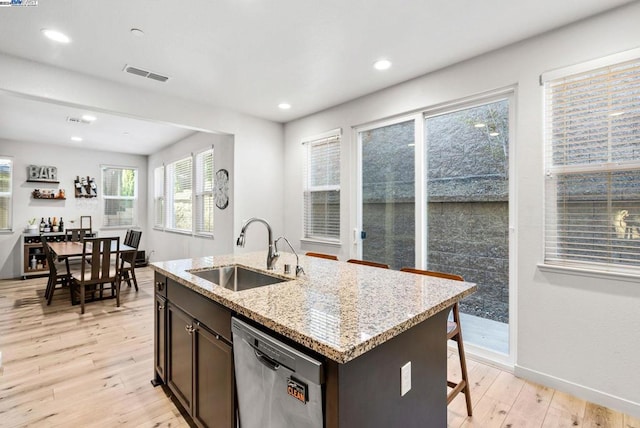 kitchen with sink, light hardwood / wood-style flooring, stainless steel dishwasher, an island with sink, and dark brown cabinets