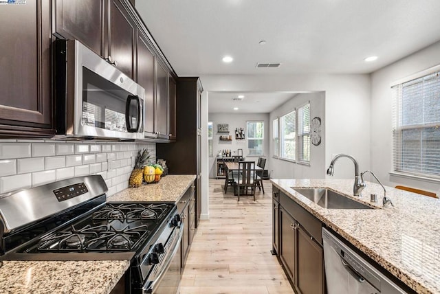 kitchen featuring light stone countertops, sink, appliances with stainless steel finishes, and light hardwood / wood-style flooring