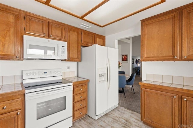 kitchen with white appliances, tile counters, and light wood-type flooring