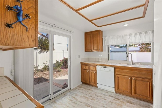 kitchen featuring light hardwood / wood-style floors, tile counters, dishwasher, and sink