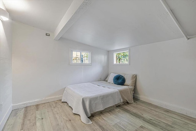 bedroom featuring vaulted ceiling with beams and light wood-type flooring