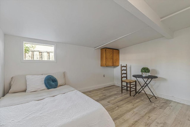 bedroom featuring beamed ceiling and light wood-type flooring