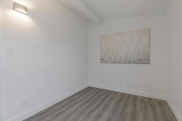 spare room featuring beam ceiling, dark hardwood / wood-style flooring, and wooden ceiling