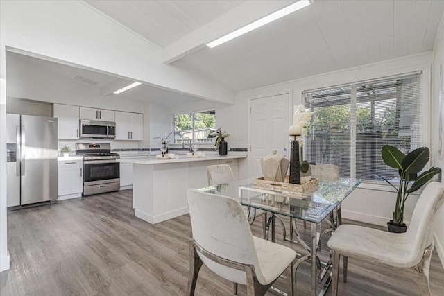 dining space featuring light hardwood / wood-style floors and lofted ceiling with beams