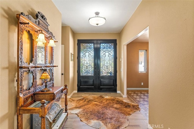 entryway featuring wood finished floors, french doors, and baseboards