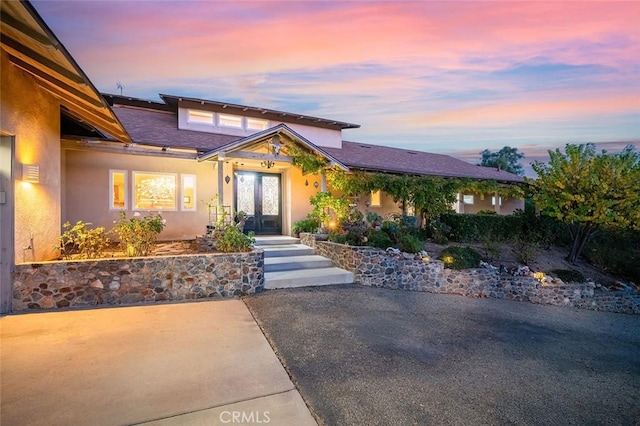 view of front of home with a shingled roof, french doors, and stucco siding