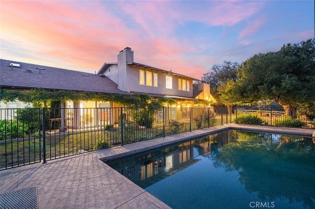 pool at dusk featuring a patio