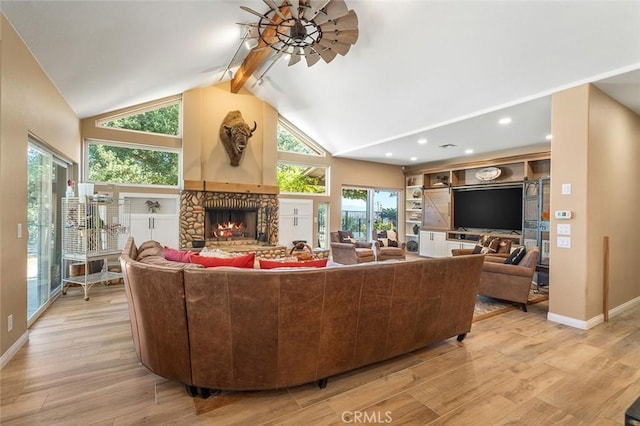 living room featuring high vaulted ceiling, a ceiling fan, a stone fireplace, light wood finished floors, and baseboards
