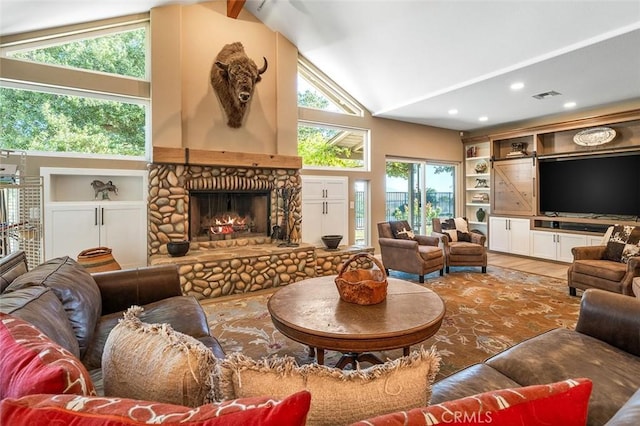 living room with visible vents, built in features, a stone fireplace, wood finished floors, and high vaulted ceiling