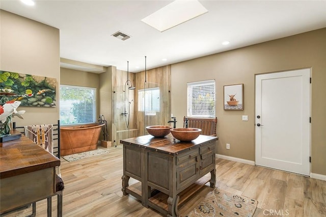 kitchen featuring baseboards, light wood-style floors, visible vents, and a sink