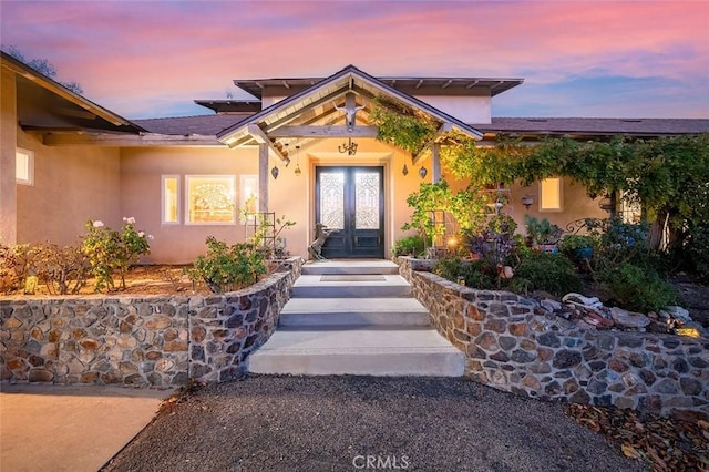 entrance to property featuring french doors and stucco siding