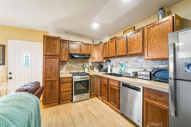 kitchen with a sink, stainless steel appliances, under cabinet range hood, and light countertops