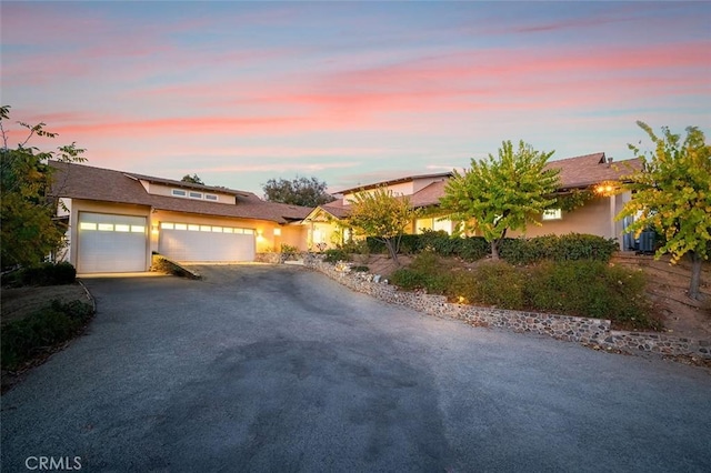 view of front of house featuring aphalt driveway, a garage, and stucco siding