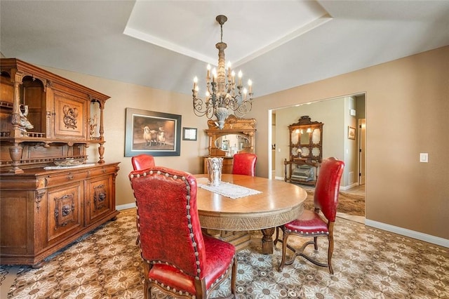 dining space with a notable chandelier, light floors, a raised ceiling, and baseboards