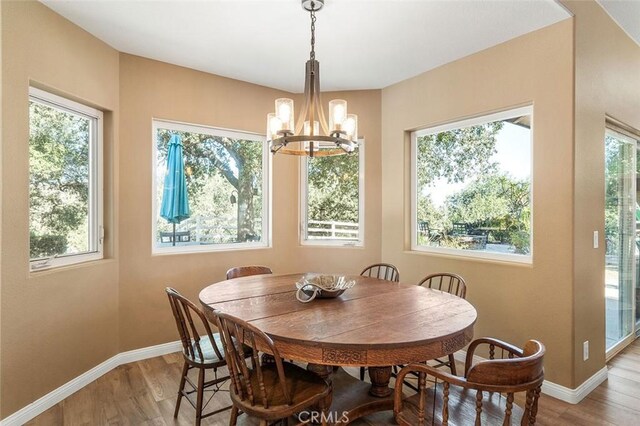 dining space with plenty of natural light, light hardwood / wood-style floors, and an inviting chandelier