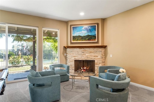 living room with recessed lighting, baseboards, a stone fireplace, and carpet flooring