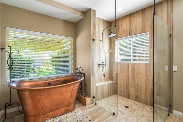 bathroom with wood-type flooring and shower with separate bathtub