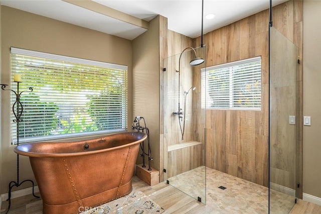 full bathroom with baseboards, a soaking tub, and walk in shower
