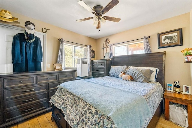 bedroom with light wood-type flooring, multiple windows, and ceiling fan